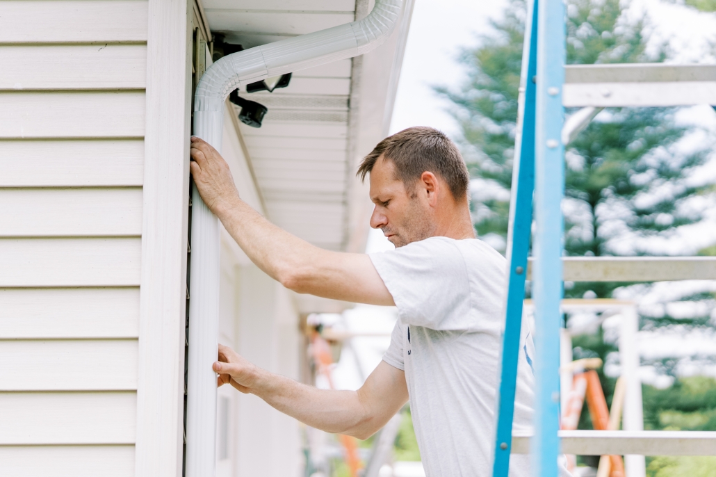 Valley Roofing team member attaching new gutters to a house.